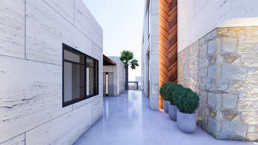 Narrow courtyard passage between villa and annex with stone and travertine walls, potted shrubs, and view toward the garden.